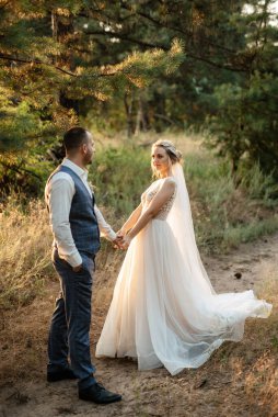 the groom and the bride are walking in the forest on a bright day