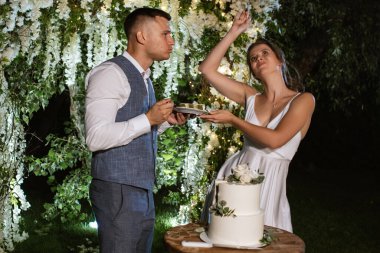 newlyweds happily cut, laugh and taste the wedding cake