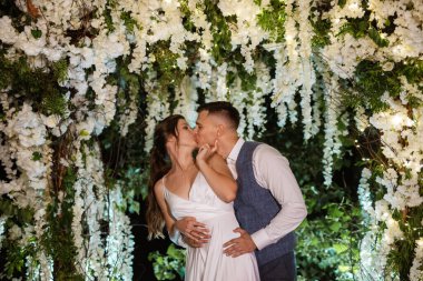 young couple of newlyweds on the evening illuminated arch