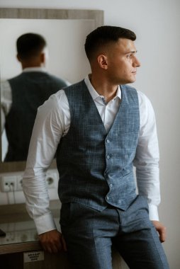 Açık gri takım elbiseli damadın portresi.