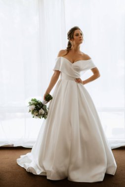 preparations for the bride with the dressing of the wedding dress in the studio