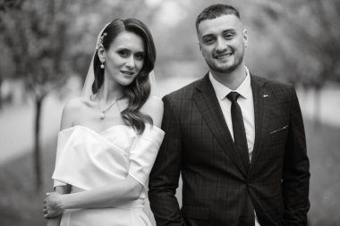 newlyweds walk in the park on the grass among cherry blossoms
