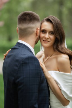 newlyweds walk in the park on the grass among cherry blossoms