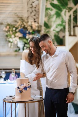 newlyweds happily cut, laugh and taste the wedding cake