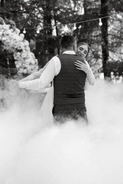 the first wedding dance of the bride and groom on a green meadow near the wedding arch