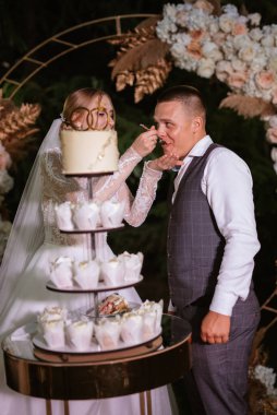 newlyweds happily cut, laugh and taste the wedding cake