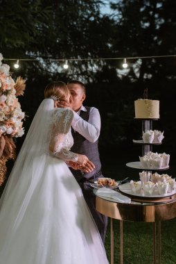 newlyweds happily cut, laugh and taste the wedding cake