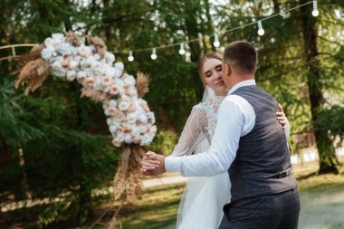 the first wedding dance of the bride and groom on a green meadow near the wedding arch