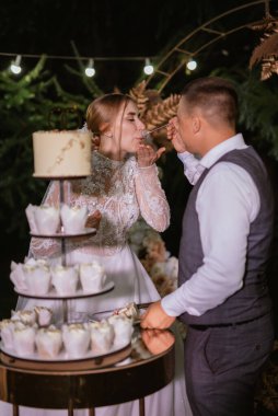 newlyweds happily cut, laugh and taste the wedding cake