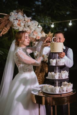 newlyweds happily cut, laugh and taste the wedding cake