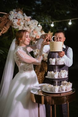 newlyweds happily cut, laugh and taste the wedding cake