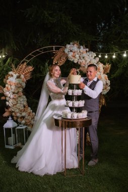 newlyweds happily cut, laugh and taste the wedding cake