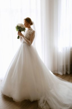portrait of a bride in the morning before the wedding with putting on a white dress