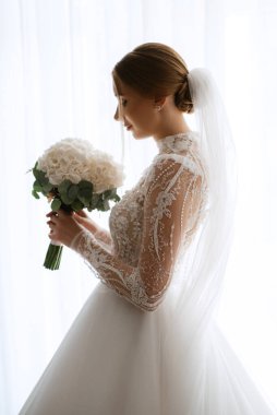 portrait of a bride in the morning before the wedding with putting on a white dress