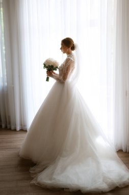 portrait of a bride in the morning before the wedding with putting on a white dress