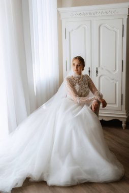 portrait of a bride in the morning before the wedding with putting on a white dress