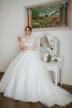 portrait of a bride in the morning before the wedding with putting on a white dress