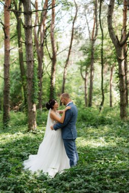 wedding walk of the bride and groom in the deciduous forest in summer