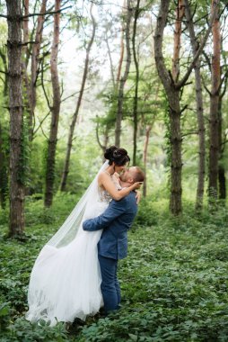wedding walk of the bride and groom in the deciduous forest in summer