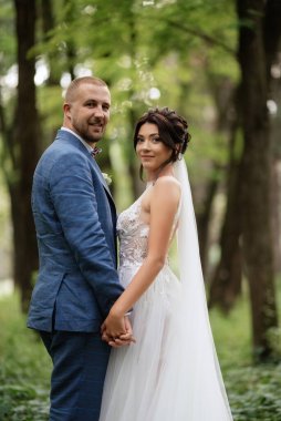 wedding walk of the bride and groom in the deciduous forest in summer
