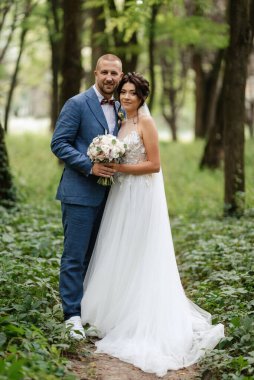 wedding walk of the bride and groom in the deciduous forest in summer