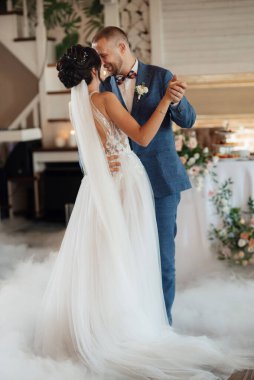 the first dance of the bride and groom inside a restaurant with heavy smoke