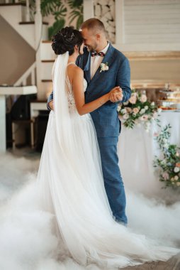 the first dance of the bride and groom inside a restaurant with heavy smoke