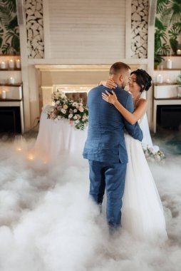 the first dance of the bride and groom inside a restaurant with heavy smoke