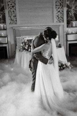 the first dance of the bride and groom inside a restaurant with heavy smoke