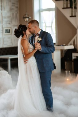 the first dance of the bride and groom inside a restaurant with heavy smoke