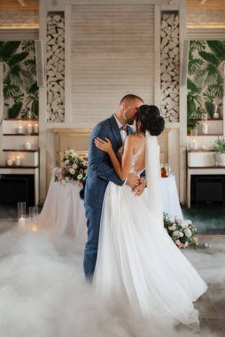 the first dance of the bride and groom inside a restaurant with heavy smoke