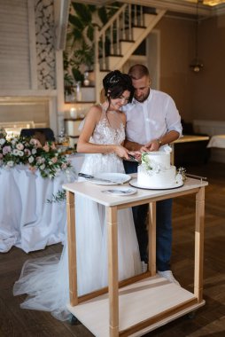 newlyweds happily cut, laugh and taste the wedding cake