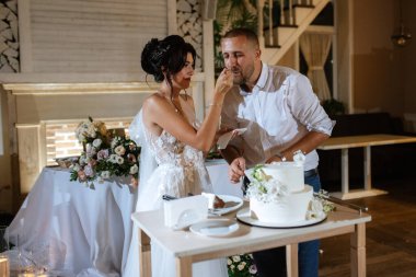 newlyweds happily cut, laugh and taste the wedding cake