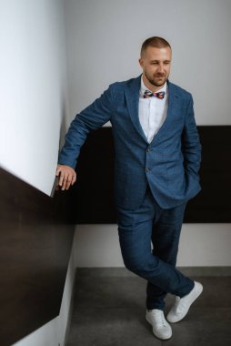 portrait of smiling groom with beard in blue color suit