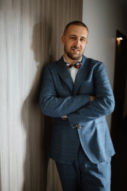 portrait of smiling groom with beard in blue color suit