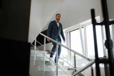 portrait of smiling groom with beard in blue color suit