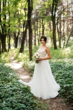 portrait of an elegant bride girl on a path in a deciduous forest