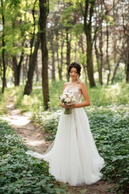 portrait of an elegant bride girl on a path in a deciduous forest