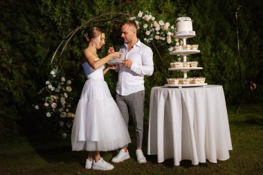 newlyweds happily cut, laugh and taste the wedding cake
