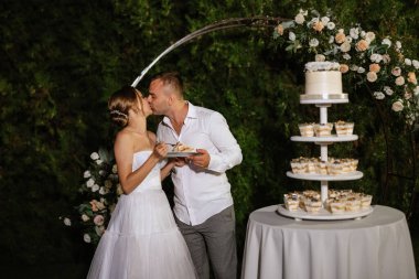 newlyweds happily cut, laugh and taste the wedding cake