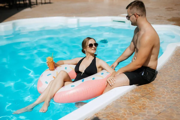 stock image guy and a girl in bathing suits are relaxing, sunbathing and having fun near the blue pool