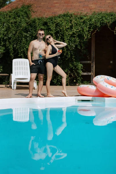 stock image guy and a girl in bathing suits are relaxing, sunbathing and having fun near the blue pool