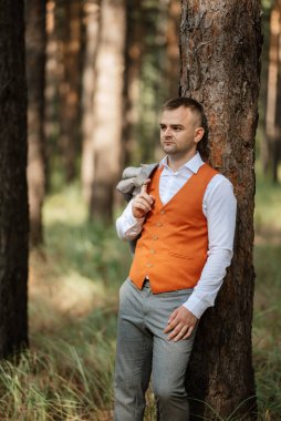 Gri takım elbiseli, turuncu yelekli ve beyaz spor ayakkabılı damadın portresi.