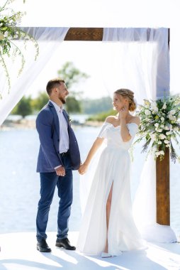 wedding ceremony on a high pier near the river with invited guests