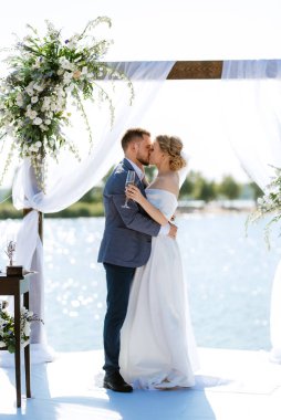 wedding ceremony on a high pier near the river with invited guests