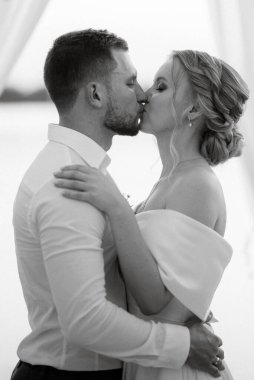 Gelin ve damat, nehrin kıyısındaki bir iskelede sarı bir günbatımının arkaplanına karşı.