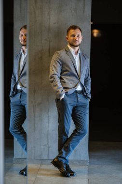 portrait of smiling groom with beard in blue color suit