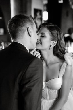 Gelin ve damat bir kokteyl barının içinde. Parlak bir atmosferde, bir bardak içkiyle.