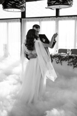 the first dance of the bride and groom inside a restaurant with heavy smoke