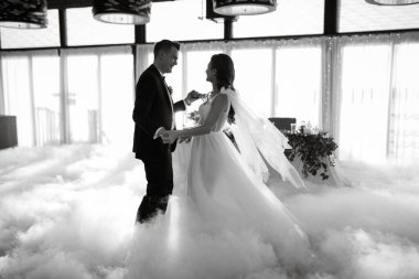 the first dance of the bride and groom inside a restaurant with heavy smoke